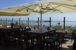 An outdoor dining area with tables and chairs, overlooking a body of water with piers. - Baltic Sea holiday home Scharbeutz (Scharbeutz)