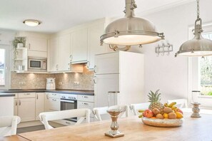 A modern kitchen with white cabinetry, stainless steel appliances, and pendant lighting. - Baltic Sea holiday home Scharbeutz (Scharbeutz)