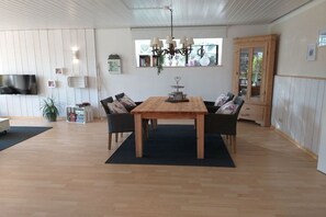 Ein Essbereich mit einem Holztisch und Stühlen, einer Chandelüster und einem Fernseher an der Wand.