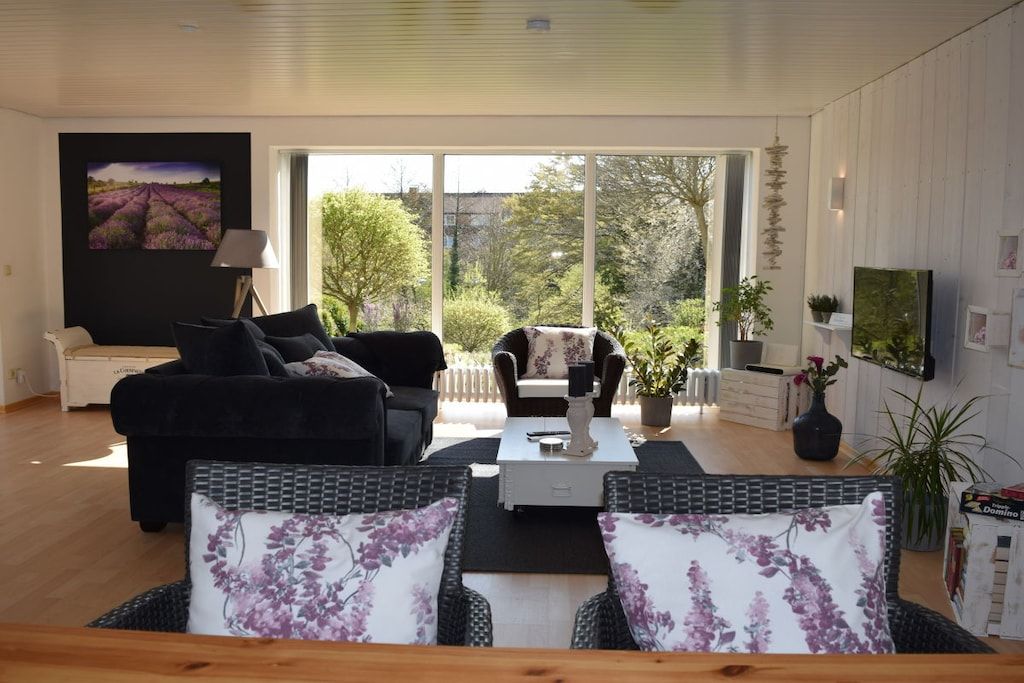 Ein Wohnzimmer mit einer Couch, Sesseln, einem Couchtisch und einem Bild an der Wand.