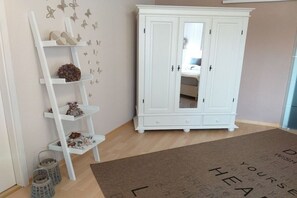 A room with a white wardrobe, a white ladder shelf, and a doormat with text. - Tanja's Baltic Sea dream home (Lütjenburg)