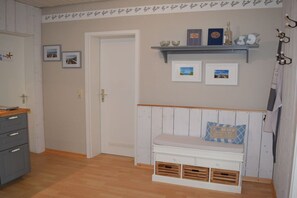 A room with a wooden bench, a door, and a shelf with decorative items. - Tanja's Baltic Sea dream home (Lütjenburg)