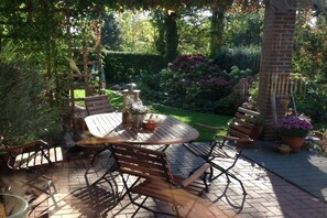 A patio with a round table and chairs, surrounded by potted plants and a brick wall. - Tanja's Baltic Sea dream home (Lütjenburg)