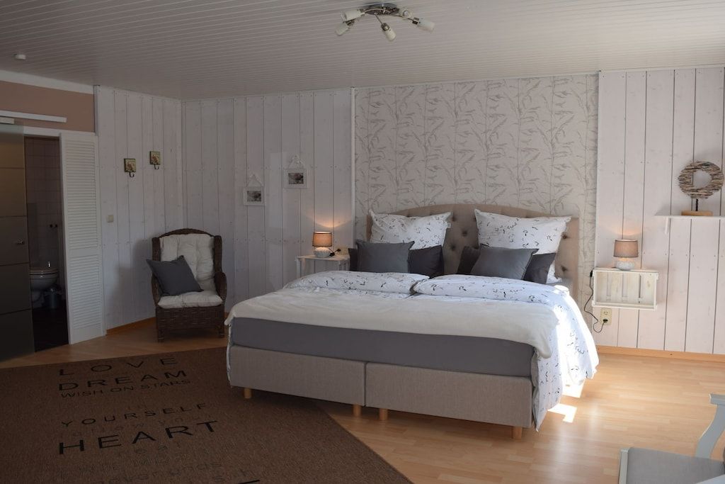 A bedroom with a bed, bedside tables, a chair, and a door.
