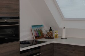 A modern kitchen with a built-in oven, a microwave, and a countertop with a picture frame and kitchen items. - Swallow's nest upper floor (Maasholm)
