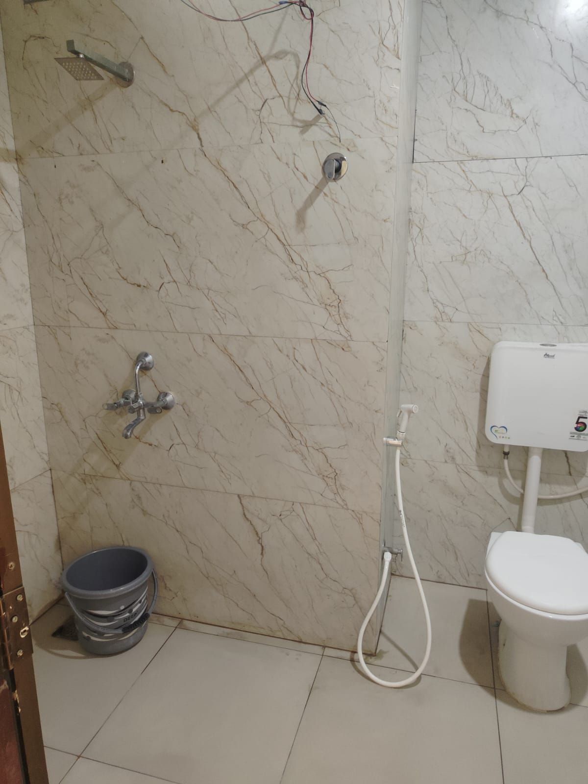 Un baño con pared de mármol, inodoro, bidé y ducha.