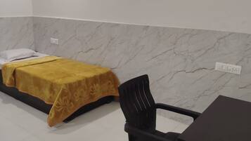 Habitación de hotel con cama, una silla, una mesa y una pared de mármol.