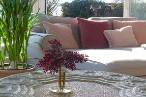 A living room with a sofa, cushions, a potted plant, and a decorative glass table. - Holiday apartment with 2 bedrooms (Lütjenholm)