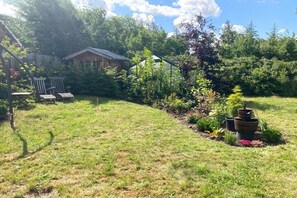 A grassy backyard with a wooden deck, a small shed, and a greenhouse. - Holiday apartment with 2 bedrooms (Lütjenholm)