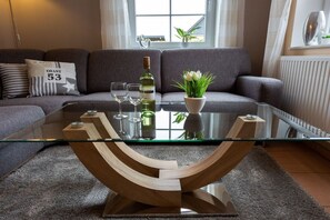 A modern living room with a glass coffee table, a bottle of wine, and a potted plant. - Baltic Sea holiday home II 300m to the beach (24398 Ostseebad Schönhagen)