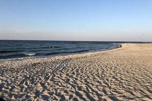 A sandy beach with gentle waves, a clear sky, and a distant pier. - Baltic Sea holiday home II 300m to the beach (24398 Ostseebad Schönhagen)