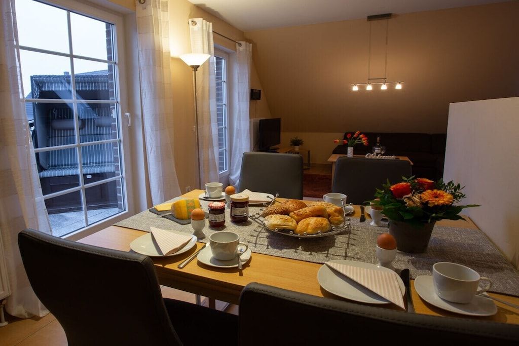 Ein Frühstückstisch für zwei Personen mit Croissants, Kaffee und einer Blumenkomposition.