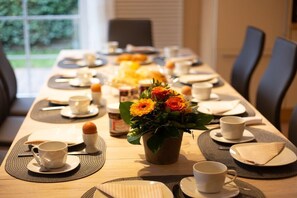 A dining table set for breakfast with cups, plates, and a flower centerpiece. - Baltic Sea holiday home II 300m to the beach (24398 Ostseebad Schönhagen)