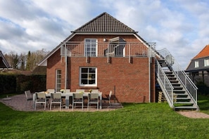 A two-story brick house with a balcony, a staircase, and a patio with outdoor furniture. - Baltic Sea holiday home II 300m to the beach (24398 Ostseebad Schönhagen)