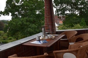An outdoor seating area with wicker chairs, a table, and a brick column. - Holiday apartment at the Baltic Sea resort (Flensburg)