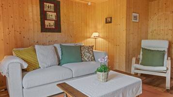 Ein gemütliches Zimmer mit einer Couch, einem Sessel, einem Tisch und einer Lampe.
