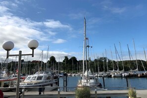 Ein Yachthafen mit mehreren Segelbooten, bewölkter Himmel und ruhiger Wasserfläche.