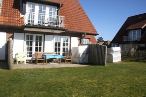 A residential property with a two-story house, a balcony, a covered patio with outdoor furniture, and a fenced yard. - Holiday apartment in Sylt with 3 bedrooms (Westerland\/ Sylt)