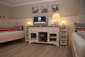 A bedroom with a bed, a TV, a nightstand, a lamp, and a cabinet. - Holiday apartment in Sylt with 3 bedrooms (Westerland\/ Sylt)