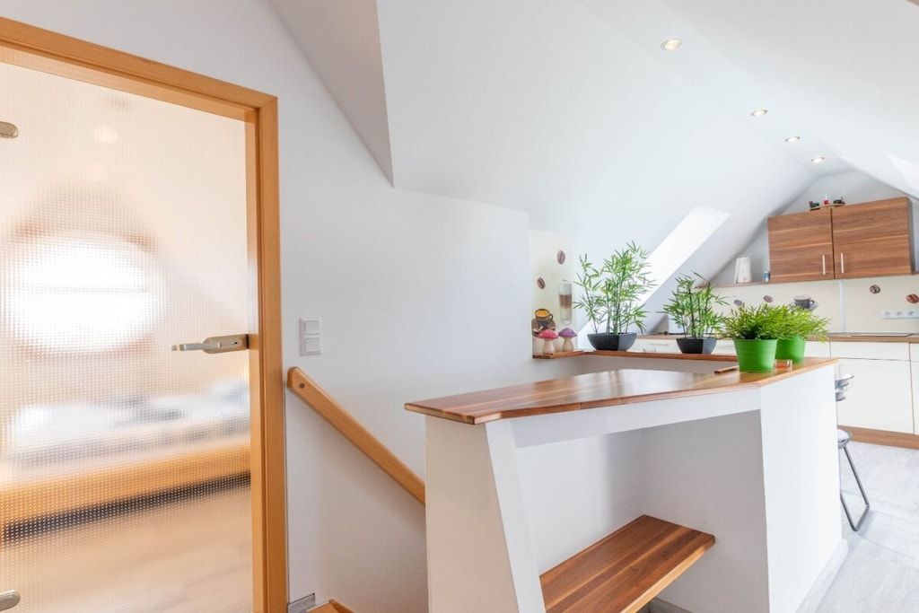 Een moderne keuken met een houten aanrecht, witte kastjes en potplanten.