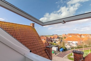 A view from a window overlooking a residential area with red-tiled roofs and a clear sky. - Holiday apartment with 1 bedroom (Norddeich)