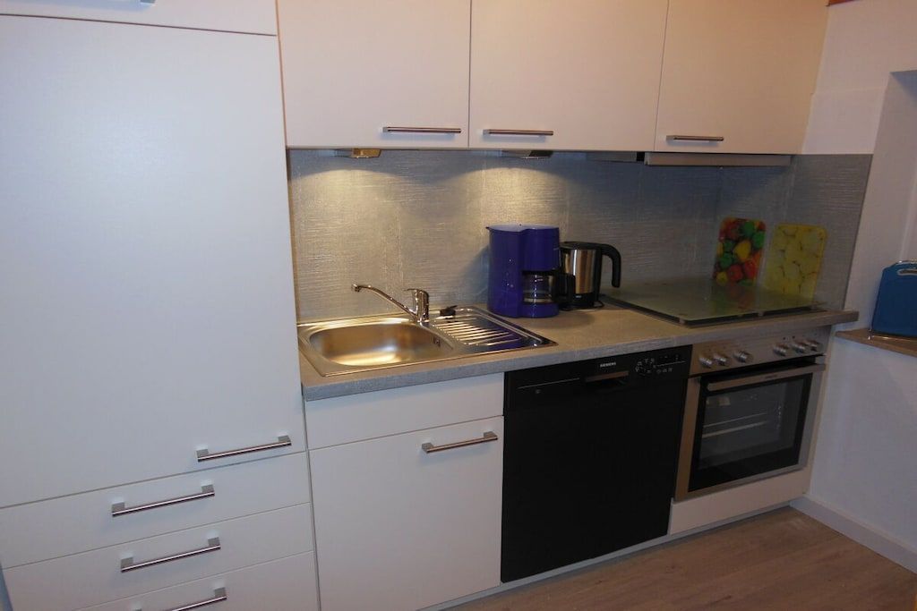 A compact kitchen with a dishwasher, oven, and a coffee maker.