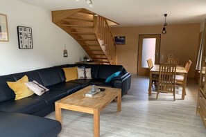 A living room with a black sofa, wooden coffee table, and a staircase. - Holiday home with 3 bedrooms (Wangerland \/ Hooksiel)
