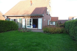 Een huis met twee verdiepingen, een pannendak, een voordeur en een zichtbare garage.