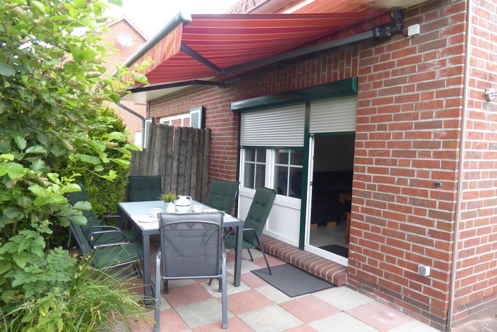 A patio with a table and chairs, a brick wall, and a sliding door.