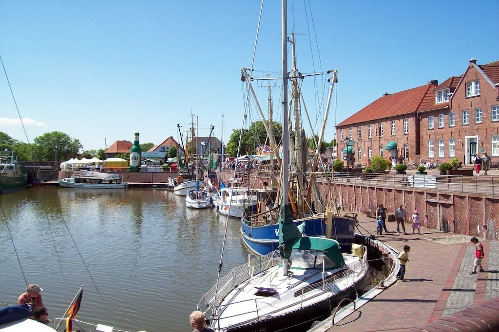 A harbor with boats docked, a building with a red roof, and a clear sky.