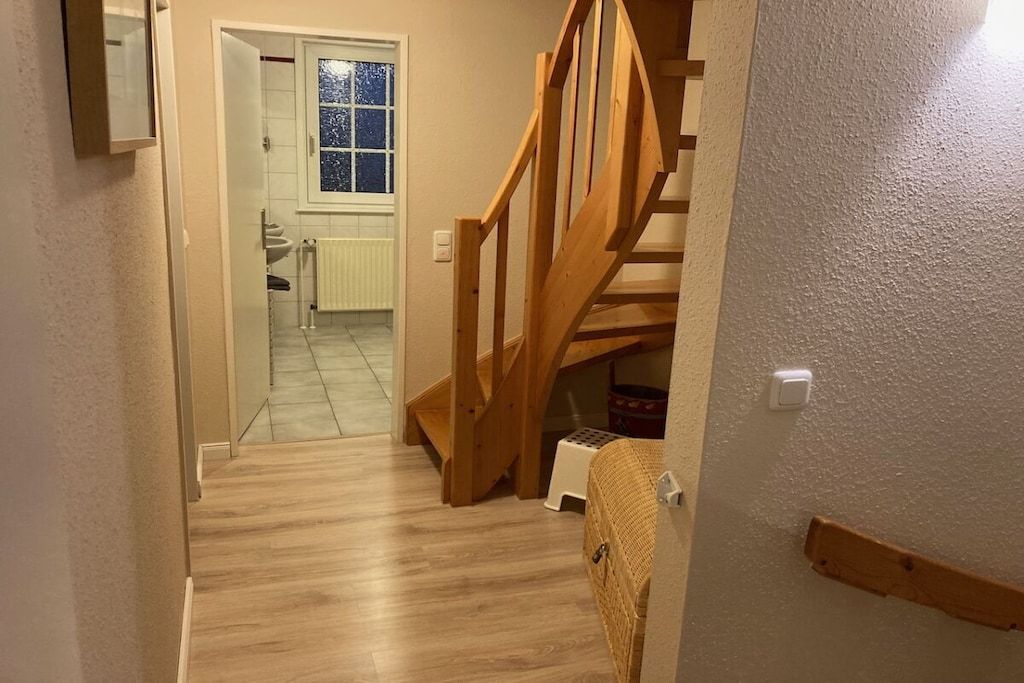 A wooden staircase leading to a bathroom with a window.