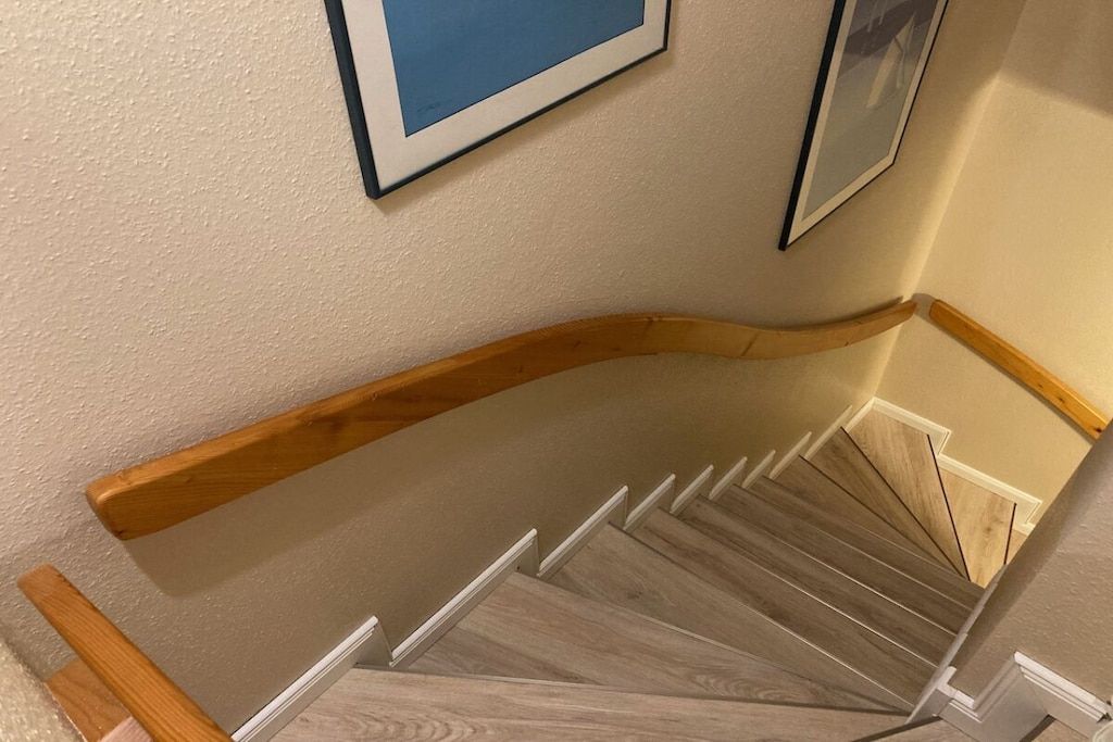 A wooden staircase with white risers and a beige wall.
