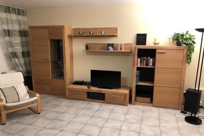 Un saló amb un sofà, un moble per a la televisió, armaris de fusta i una biblioteca.