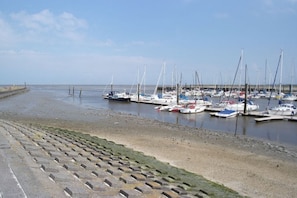 Ein Yachthafen mit vertäuten Booten am Ufer, einem klaren Himmel und einem Steinweg, der zum Wasser führt.
