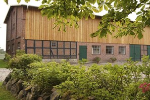 A building with a wooden facade, brick lower section, and green shutters. - White Cottage Estate Priesholz (Rabenholz)