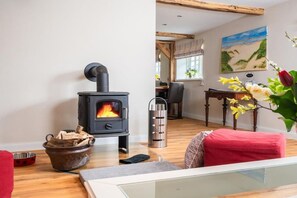 Ein gemütliches Zimmer mit Kaminofen, Essecke und einem Gemälde an der Wand.