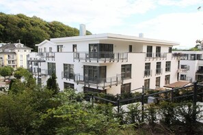 Un edifici de diverses plantes amb balcons, teulada plana i vistes a la vegetació.