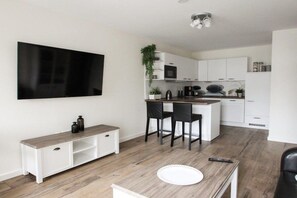 A modern kitchen with white cabinets, a wooden countertop, and a dining area with a bench and chairs. - Villa Louisa 46 - Störtebeker (Ostseebad Sellin)