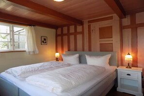 A double bed with white bedding, two bedside lamps, a nightstand, and a window with curtains. - Keitumer Chaussee 5 Holiday Apartment 2 (Sylt Westerland)