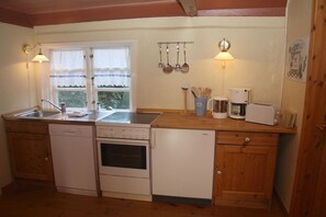 A kitchen with a dishwasher, oven, and a coffee maker. - Keitumer Chaussee 5 Holiday Apartment 2 (Sylt Westerland)