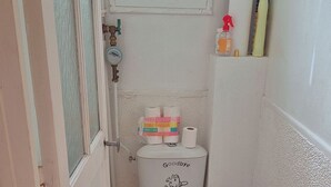 Un baño pequeño con inodoro, secamanos y soporte para papel higiénico.