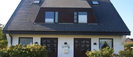 A two-story house with a dark roof, a chimney, and a sign that reads 'Gröde'.