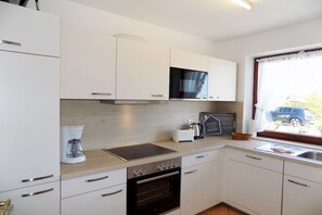 A kitchen with white cabinets, a microwave, a coffee maker, and a chalkboard sign. - House Oland Holiday Apartment 5 (Wenningstedt)
