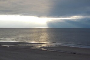 Ein Strand mit ruhiger See und bewölktem Himmel.