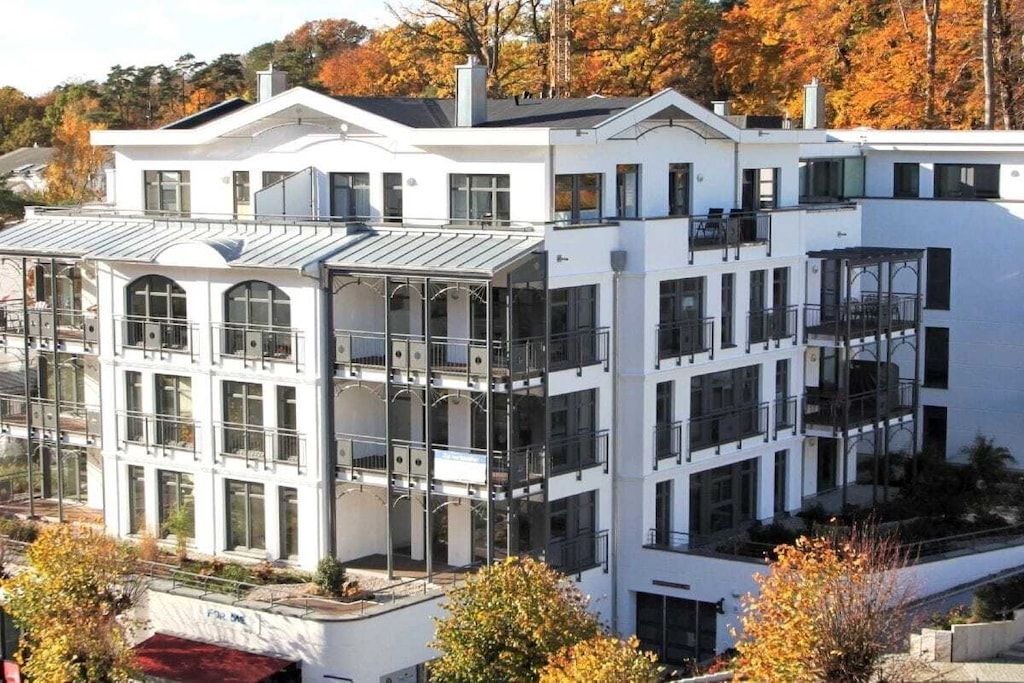 Un edificio de varios pisos con balcones, grandes ventanales y techo plano.