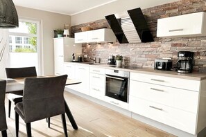 Eine moderne Küche mit weißen Schränken, einer Stein-Spritzschutzwand und einem eingebauten Backofen.