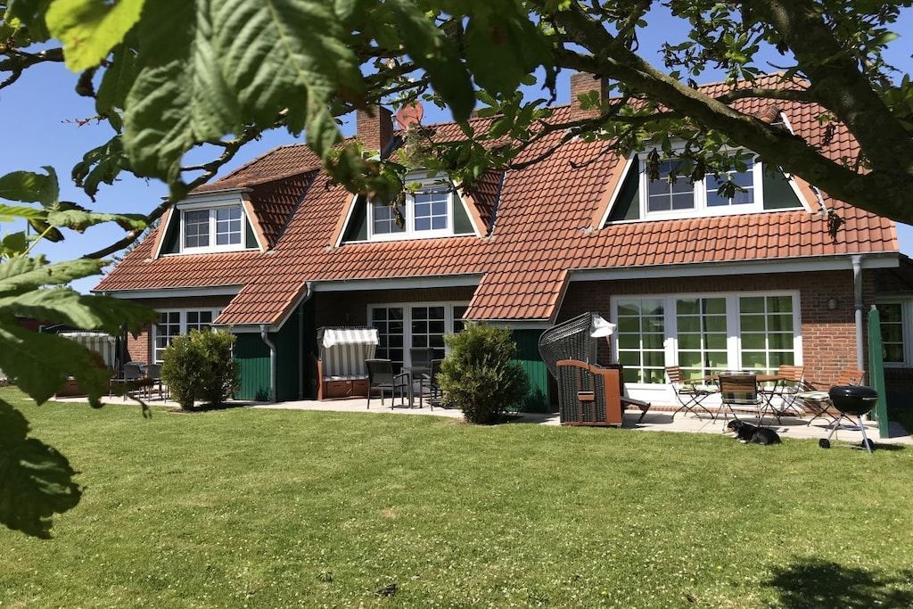 A two-story house with a sloped roof, a covered patio area, and a well-maintained lawn.