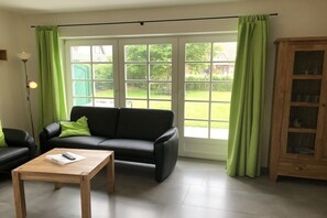 A living room with a black sofa, a wooden coffee table, and a cabinet. - Holiday home with 2 bedrooms (Friedrichskoog-Spitze)