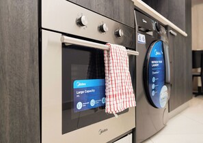 A modern kitchen with a built-in oven and a washing machine. - The Lennox Suite by HDG (Accra)