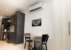 A modern kitchen with dark cabinetry, a built-in microwave, and a wall-mounted air conditioner. - The Lennox Suite by HDG (Accra)